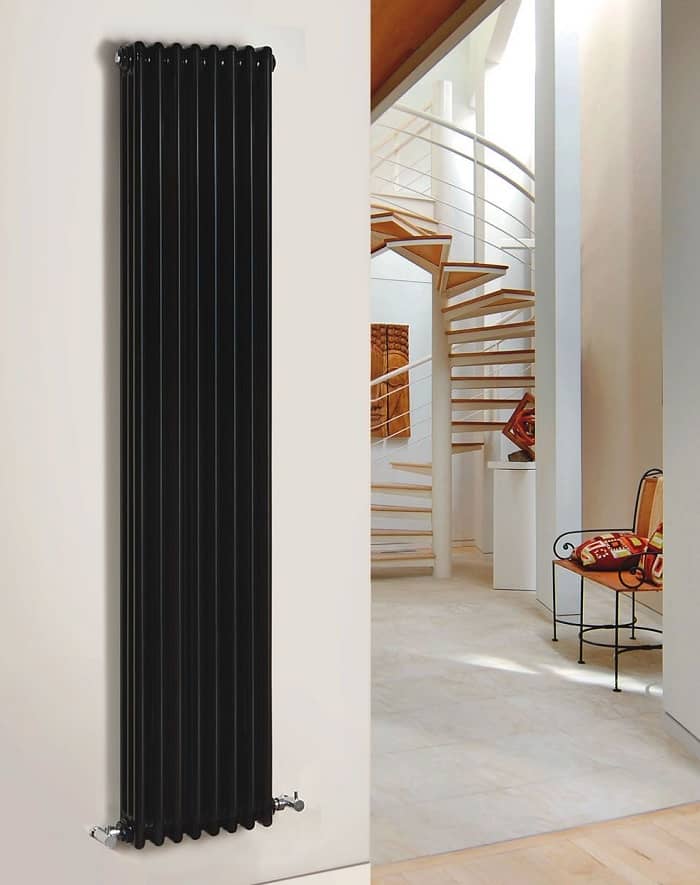 vertical black cast iron radiator on white wall